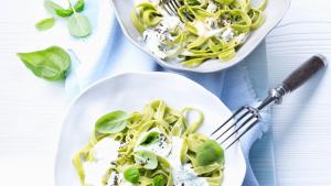 Groene pasta met pestoroomsaus en basilicum