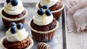 Cupcakes afgewerkt met honingfrosting en blauwe bessen