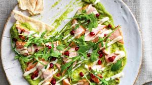 Guacamole-aioli­crème met warm­gerookte zalm, rucola en granaatappelpitten