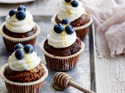 Cupcakes afgewerkt met honingfrosting en blauwe bessen