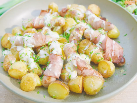 Gegrilde aardappelsalade met ranchdressing, worstjes in spek gerold en cheddar