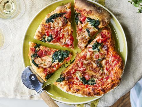Pizza met gerookte kip, spinazie, tomatenblokjes en mozzarella