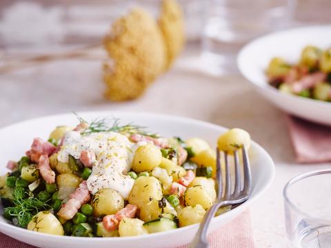 In de pan gebakken gnocchi met verse kruiden, erwten en spekjes