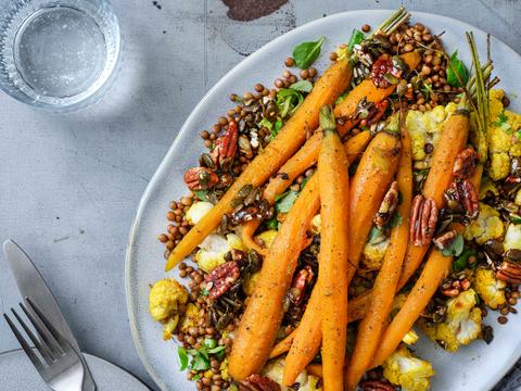 Warme linzen-bloemkoolsalade met gemberwortelen en gekaramelliseerde noten