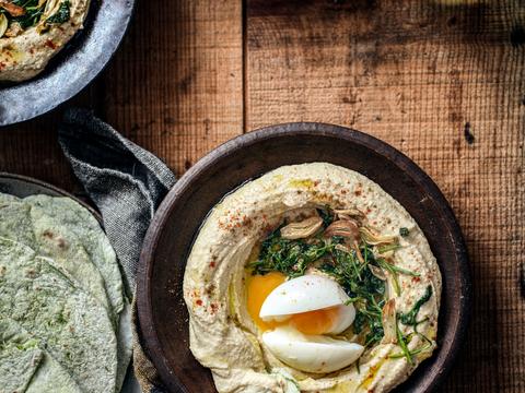 Korianderplatbrood met hummus en een topping van een zachtgekookt ei en gebakken koriander