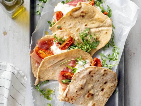 Piadina met parmaham, stracciatella, zongedroogde tomaten en rucola