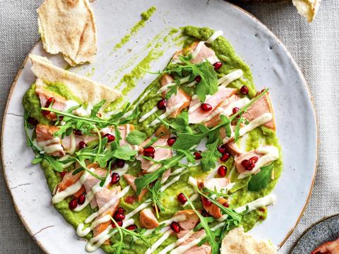 Guacamole-aioli­crème met warm­gerookte zalm, rucola en granaatappelpitten
