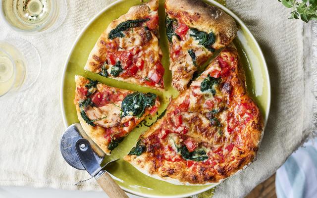 Pizza met gerookte kip, spinazie, tomatenblokjes en mozzarella