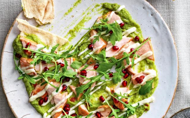 Guacamole-aioli­crème met warm­gerookte zalm, rucola en granaatappelpitten