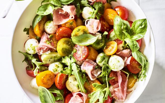 Kerstomatensalade met mozzarellabolletjes, prosciutto en kruidenvinaigrette