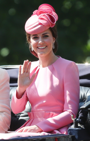 In een zuurstokroze jurk van Alexander McQueen met hoed van Jane Taylor en oorbellen in bruikleen van koningin Elizabeth II