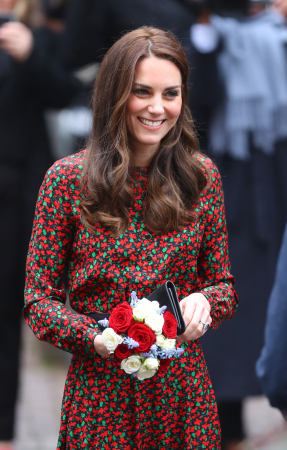 In een zwarte jurk met rood en groen bloemenmotief van Vanessa Seward met suĂšde clutch van Mulberry