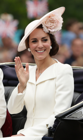 In een crÚmekleurige jurk van Alexander McQueen met hoed van Philip Treacy, halsketting van Mappin & Webb en oorbellen in bruikleen van koningin Elizabeth II