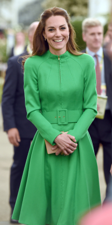 In een felgroene manteljurk van Catherine Walker met clutch van L.K.Bennett en gouden oorbellen van Kiki McDonough