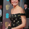 In een zwarte off-shoulderjurk met bloemenprint met zwarte clutch, beide van Alexander McQueen, en juwelen in bruikleen van koningin Elizabeth II