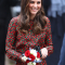 In een zwarte jurk met rood en groen bloemenmotief van Vanessa Seward met suĂšde clutch van Mulberry