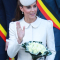 In een crĂšmekleurige mantel van Alexander McQueen met hoed van Jane Taylor, oorbellen van Kiki McDonough en clutch van Alexander McQueen