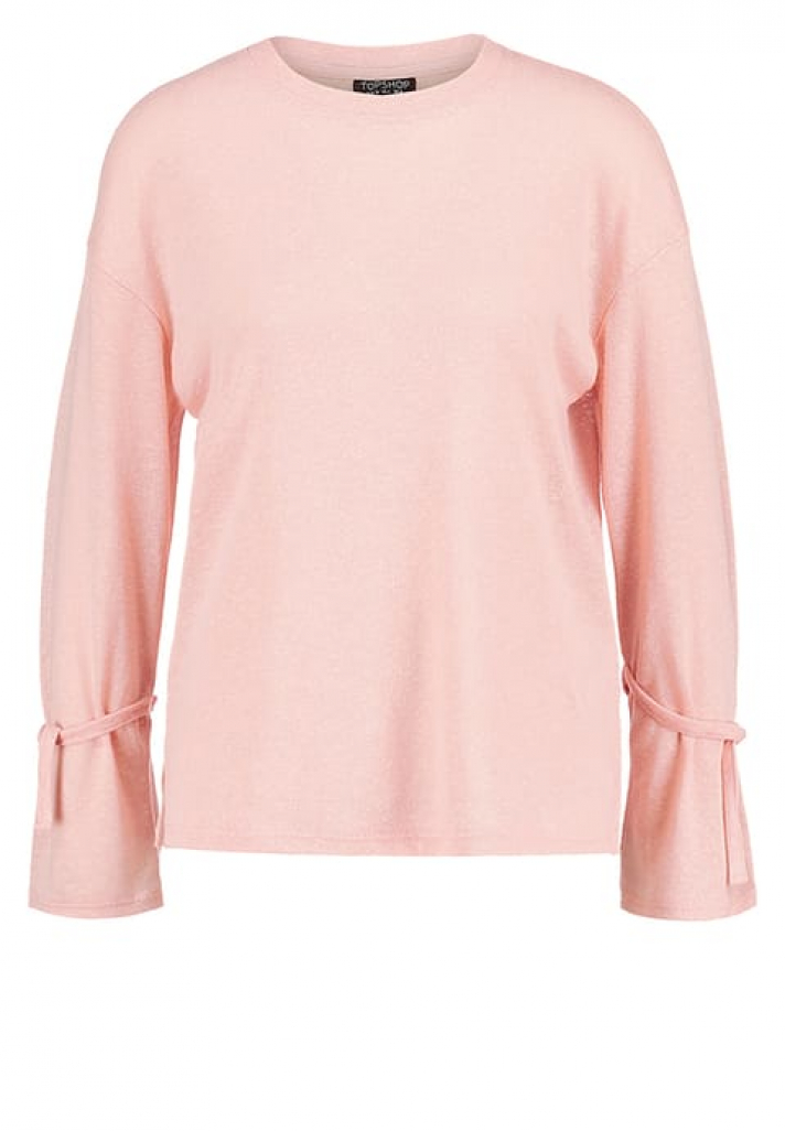 Un pull rose poudré avec des manches nouées