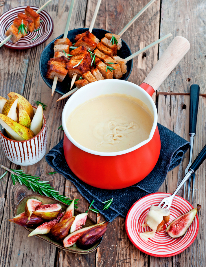Fondue au fromage classique accompagnée de brochettes de pain grillé au romarin, figues et poires