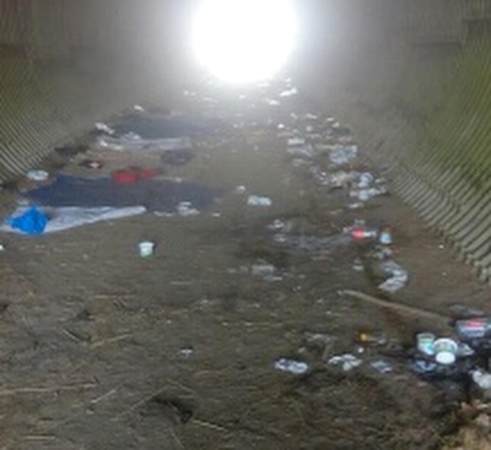 Het tunneltje onder de snelweg ligt vol afval.