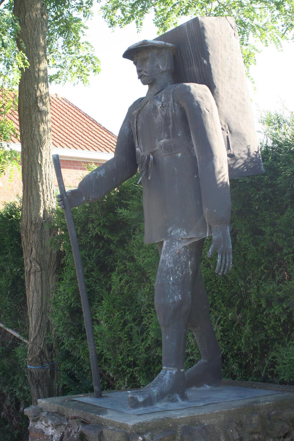 Een bronzen Karel de Brouwer torst een rugzak met onbekende inhoud.