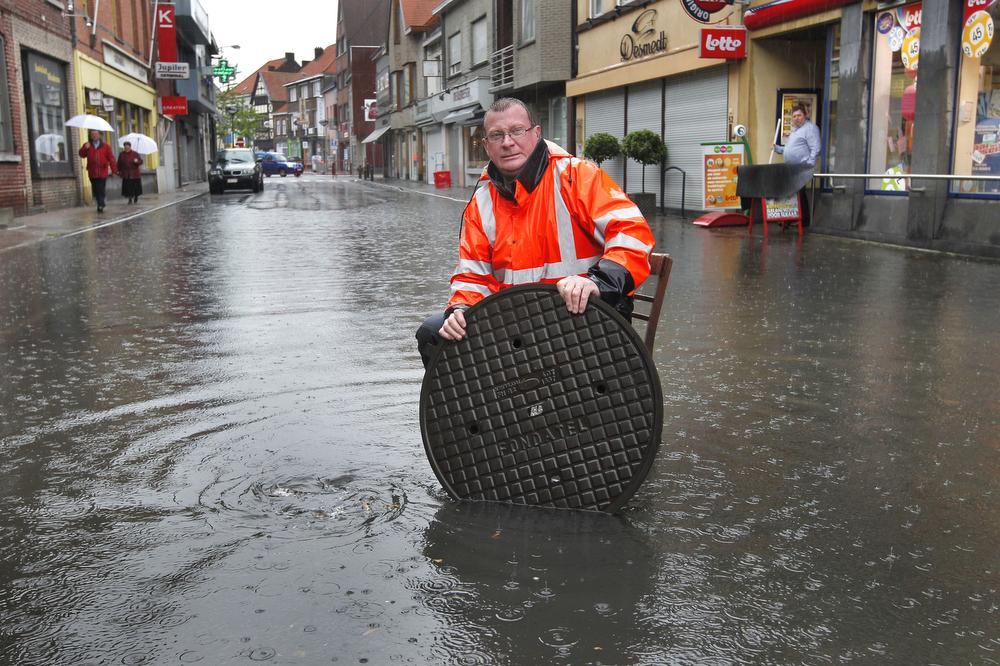 Een bijna iconische foto. Na de felle wolkbreuk van 12 juni 2012 gaat Geert Deseure de wateroverlast op het kruispunt van de Oostendestraat met de Langepijpestraat te lijf. (Foto JS)