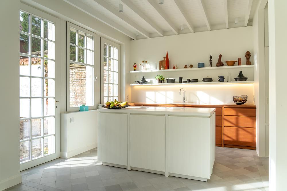De symmetrie van het huis komt ook terug in de keuken, waar het keukenraam, het keukeneiland en de deur naar de leefruimte op één lijn staan.
