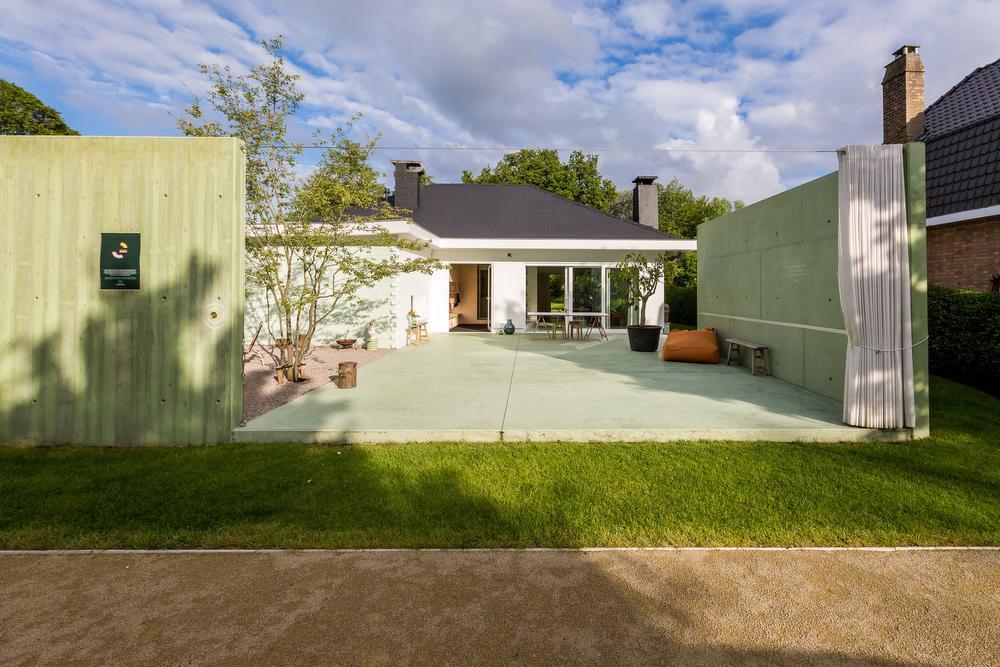 De 'voortuin' met petanqueveld, met daarachter de wanden in groen beton, die met een gordijn kunnen afgesloten worden.