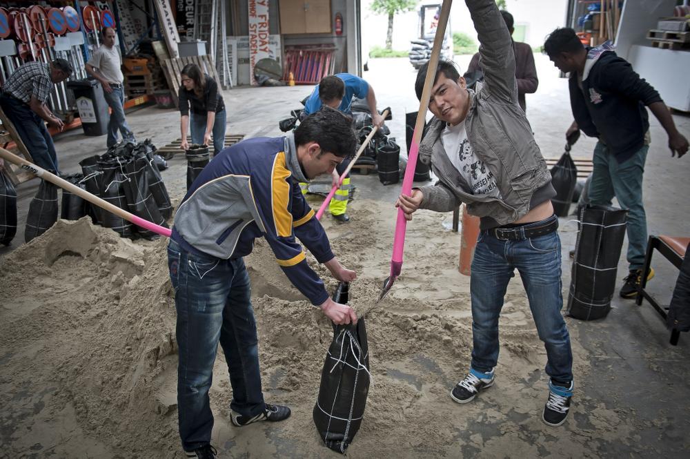 Vrijwilligers helpen zandzakjes vullen in Staden 