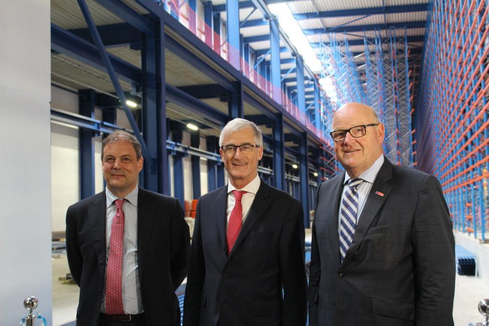 Van links naar rechts zien we CEO Charles Beauduin, Minister-President van Vlaanderen Geert Bourgeois en Schepen van Economie Rudolf Scherpereel voor het tweede nieuw bijgebouwde volautomatisch magazijn.