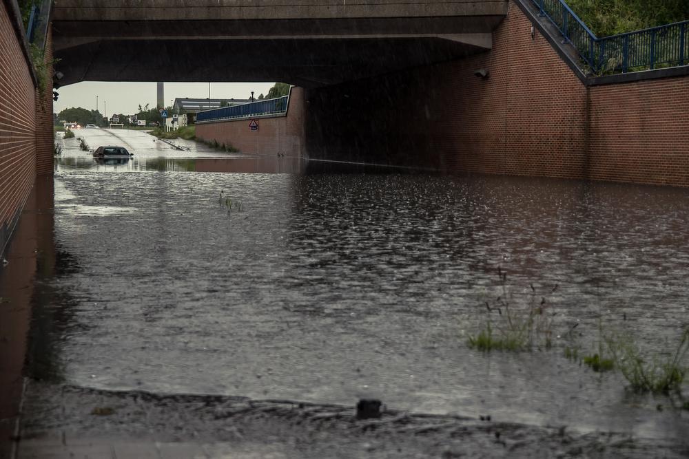 Opnieuw wateroverlast na onweer: BMW rijdt zich vast aan ondergelopen spoorwegbrug