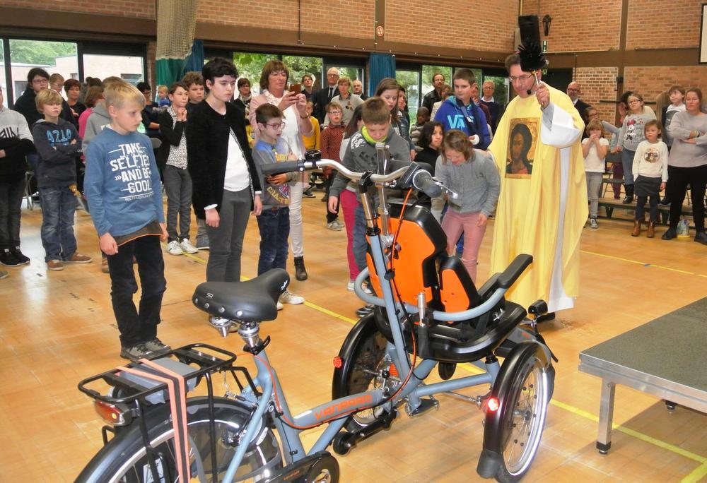 De bisschop wijdde de gloednieuwe elektrische rolstoelfiets.