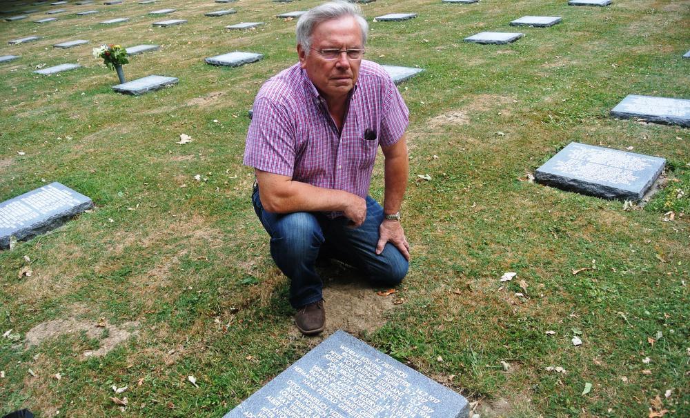 Militair luchtvaartkenner Lothair Vanoverbeke bij de grafsteen op de Duitse begraafplaats Menen Wald. De naam is fout gespeld: er staat 'Ustinor' in plaats van 'Ustinov'.