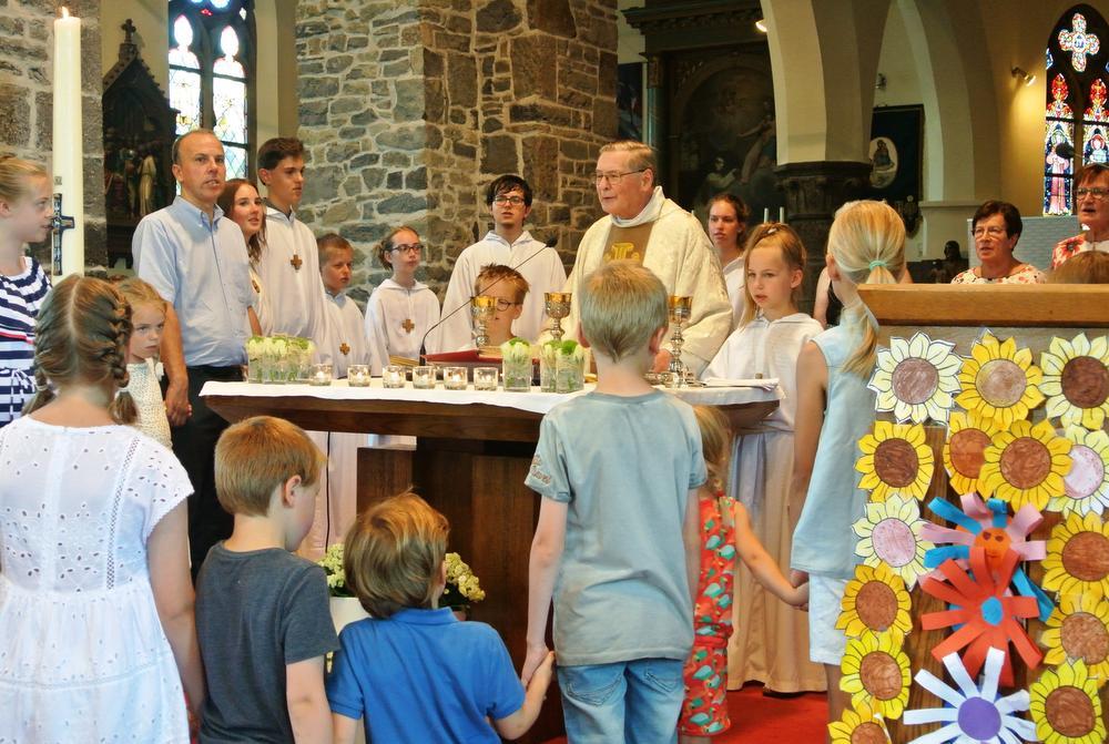 Pastoor Willy Bonte voor het laatst aan het altaar in Lendelede, omringd door parochiemedewerkers en kinderen bij het onzevader.