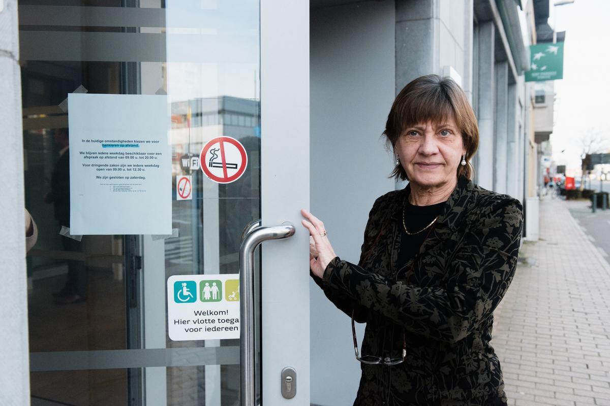 Kathleen Cosaert hangt een formulier aan de deur van haar bankkantoor.