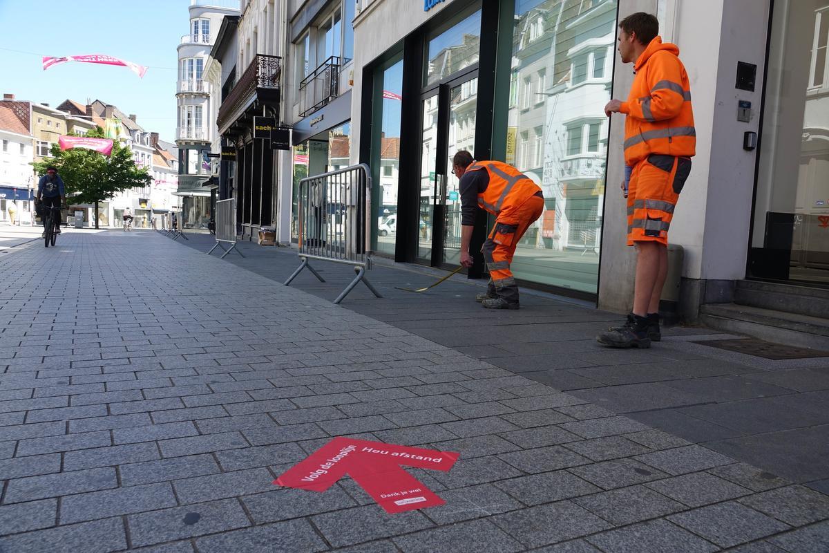 Stadsmedewerkers brengen stickers aan in het winkelwandelgebied die de mensen tonen waar ze moeten stappen. (foto AN)