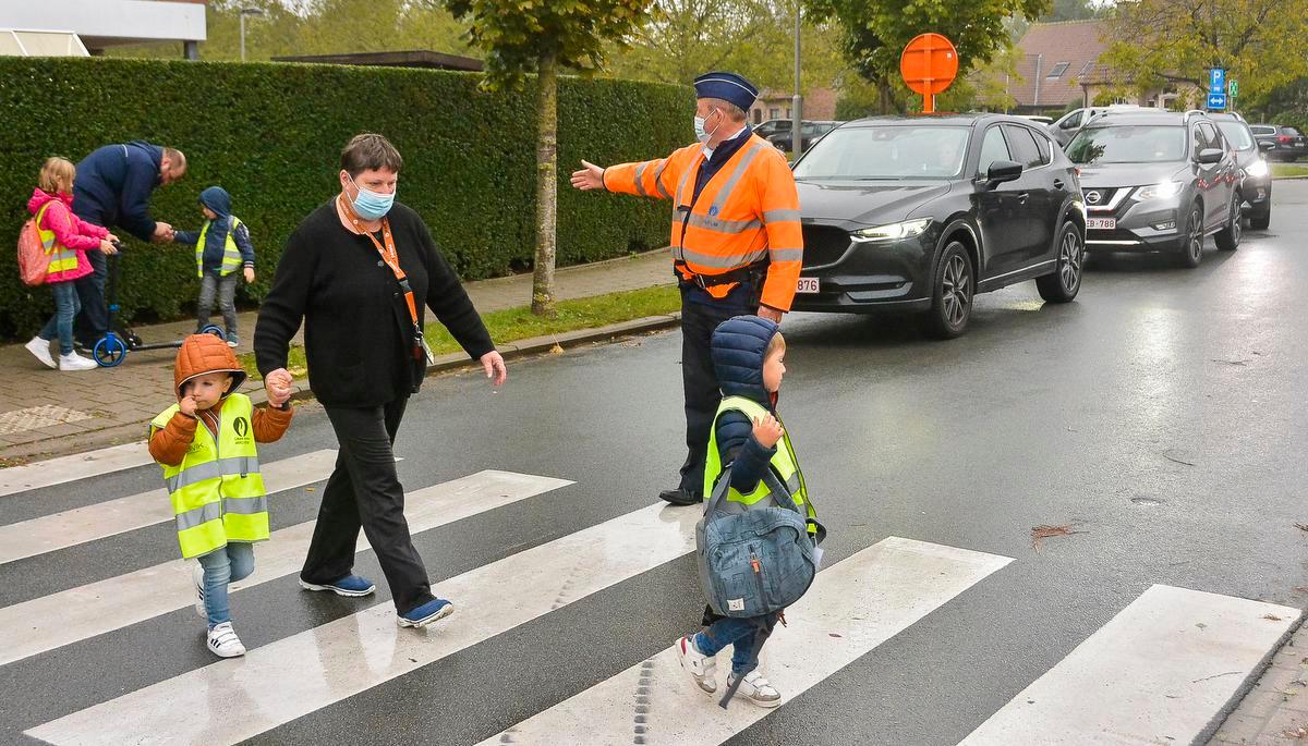 In de Tuinwijk in Geluwe, waar de ingang van De Graankorrel is gevestigd, moet het druk verkeer geleid worden door een agent. Er passeren hier honderden kinderen.