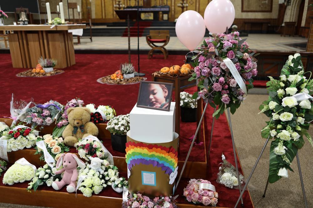 Bloemen en knuffels sieren de kist.