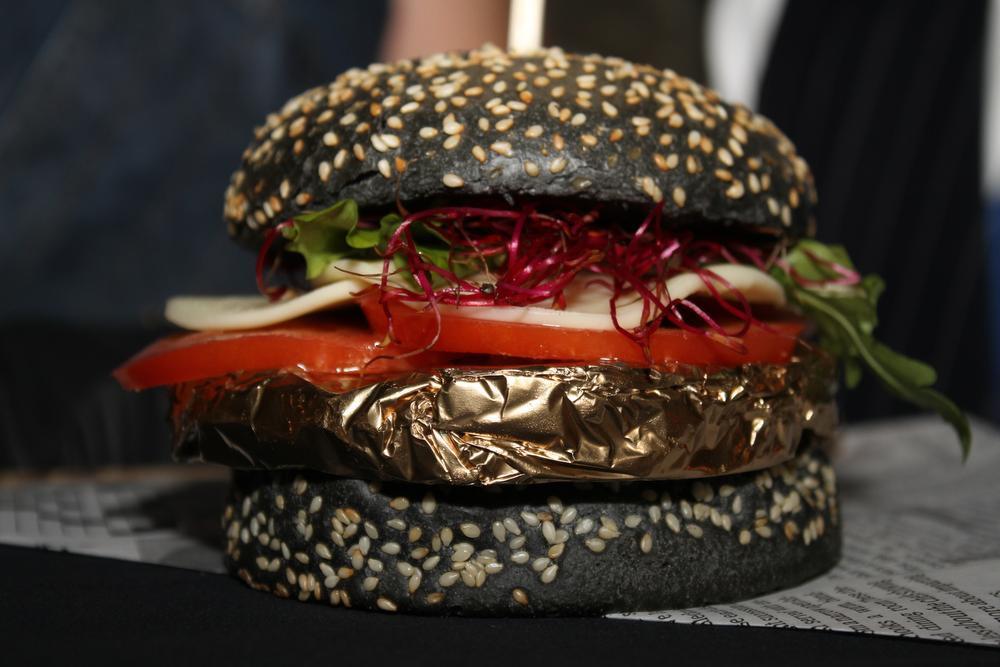De hamburger is ingepakt in bladgoud en zit in een zwart broodje.