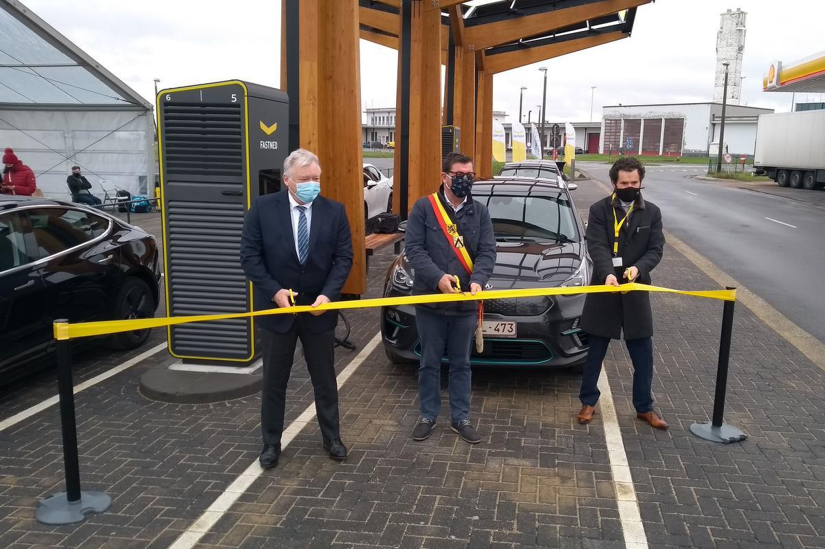 Burgemeester Bart Tommelein knipt het lint door, met links ceo Marcel Buelens van de luchthaven en rechts ceo Michiel Langezaal van Fastned.