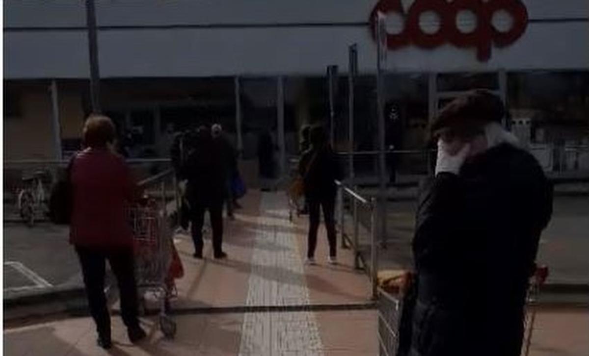 Aan de supermarkt staan mensen aan te schuiven om binnen te gaan, telkens met een meter afstand.