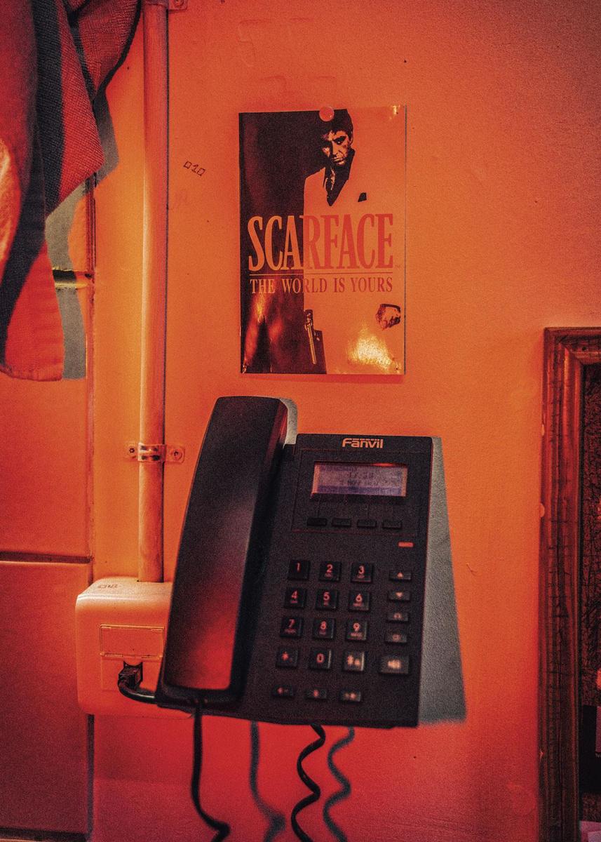 'De affiche van Scarface boven de celtelefoon. De ondertitel van de film is: The world is yours.'