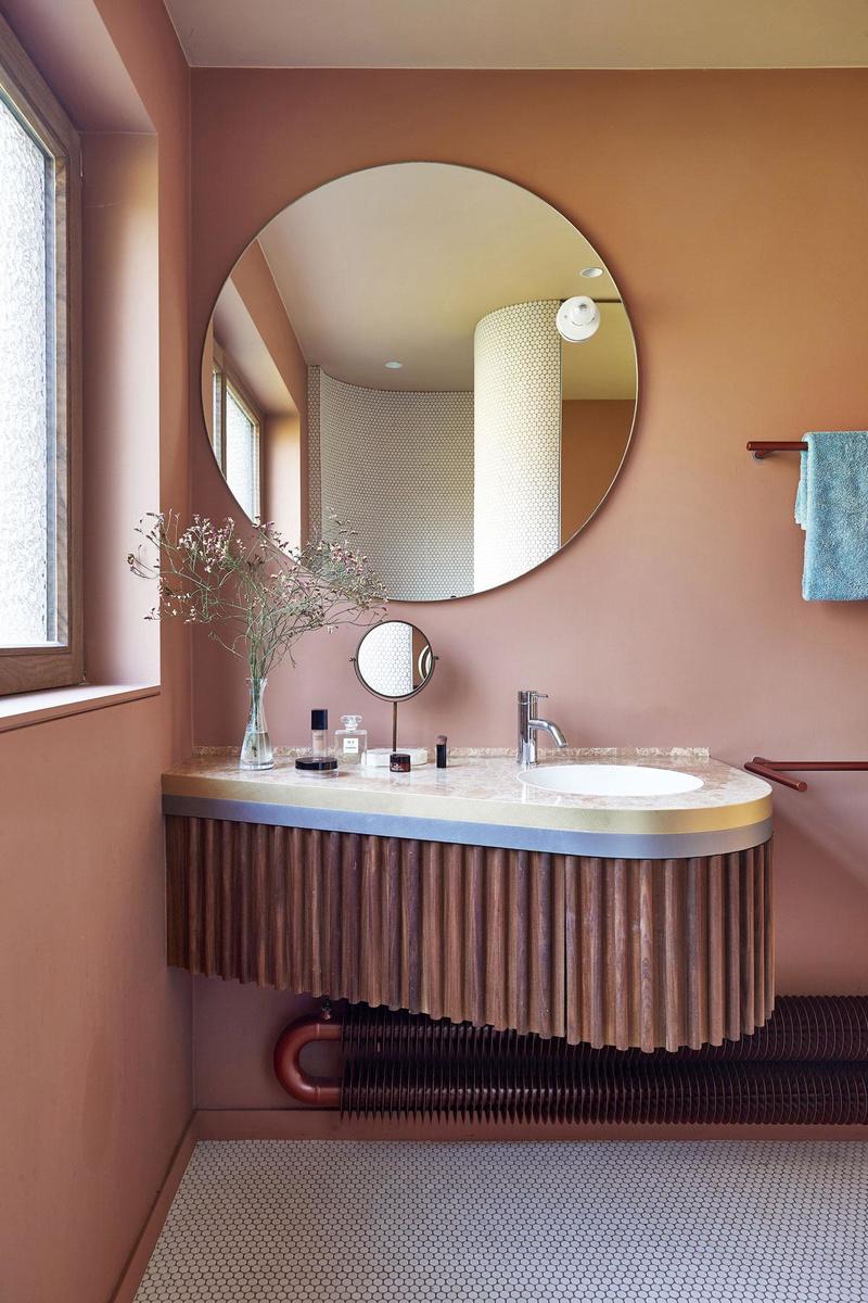 In de badkamer domineren sensuele vormen en een vrouwelijker palet van notelaar, messing en roze marmer. De tegeltjes van de douche vonden de architecten in Frankrijk.