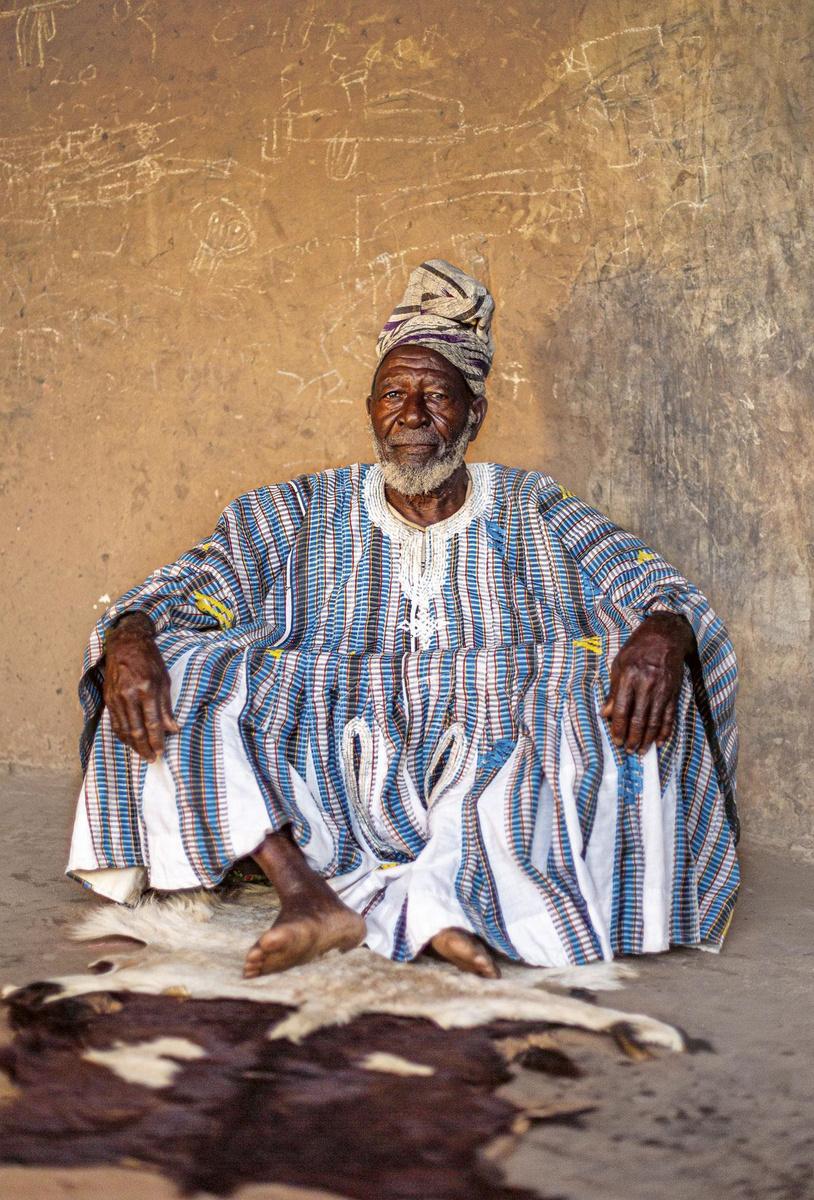 Le chef mamprusi Kulibidaana vêtu d'un batakari dans sa maison à Nalerigu (Ghana), 2015. Il est assis sur la peau de la vache tuée le jour de son accession au titre de chef, symbole de son pouvoir.