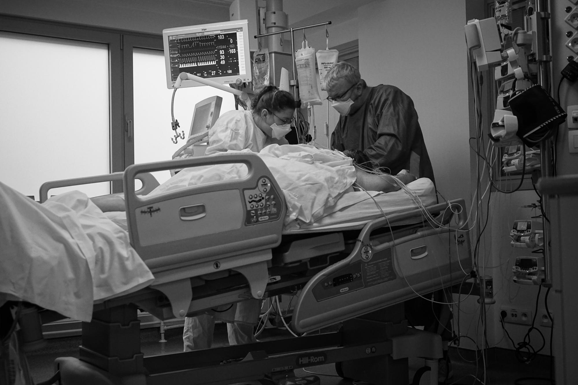 Une stagiaire et son enseignant s'occupent d'un.e patient.e placé.e dans le coma pour cause de Covid. 
