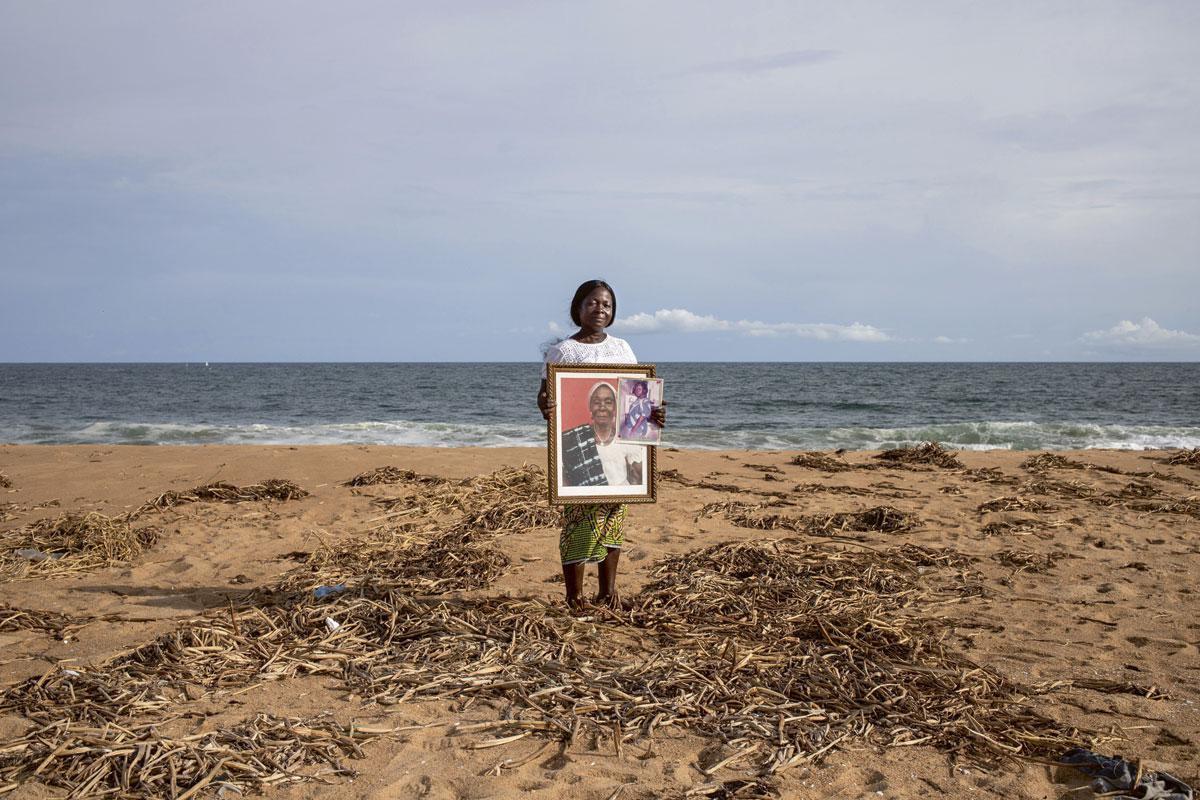 Angèle Djecket Akouba toont een ingelijste foto van haar moeder, de laatste tastbare herinnering die ze nog heeft. Het graf is compleet verdwenen.