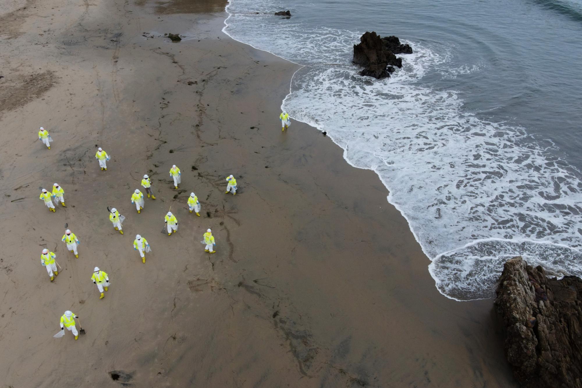 Mensen ruimen ruwe olie op die aanspoelt aan de Californische kust, 7 oktober 2021.