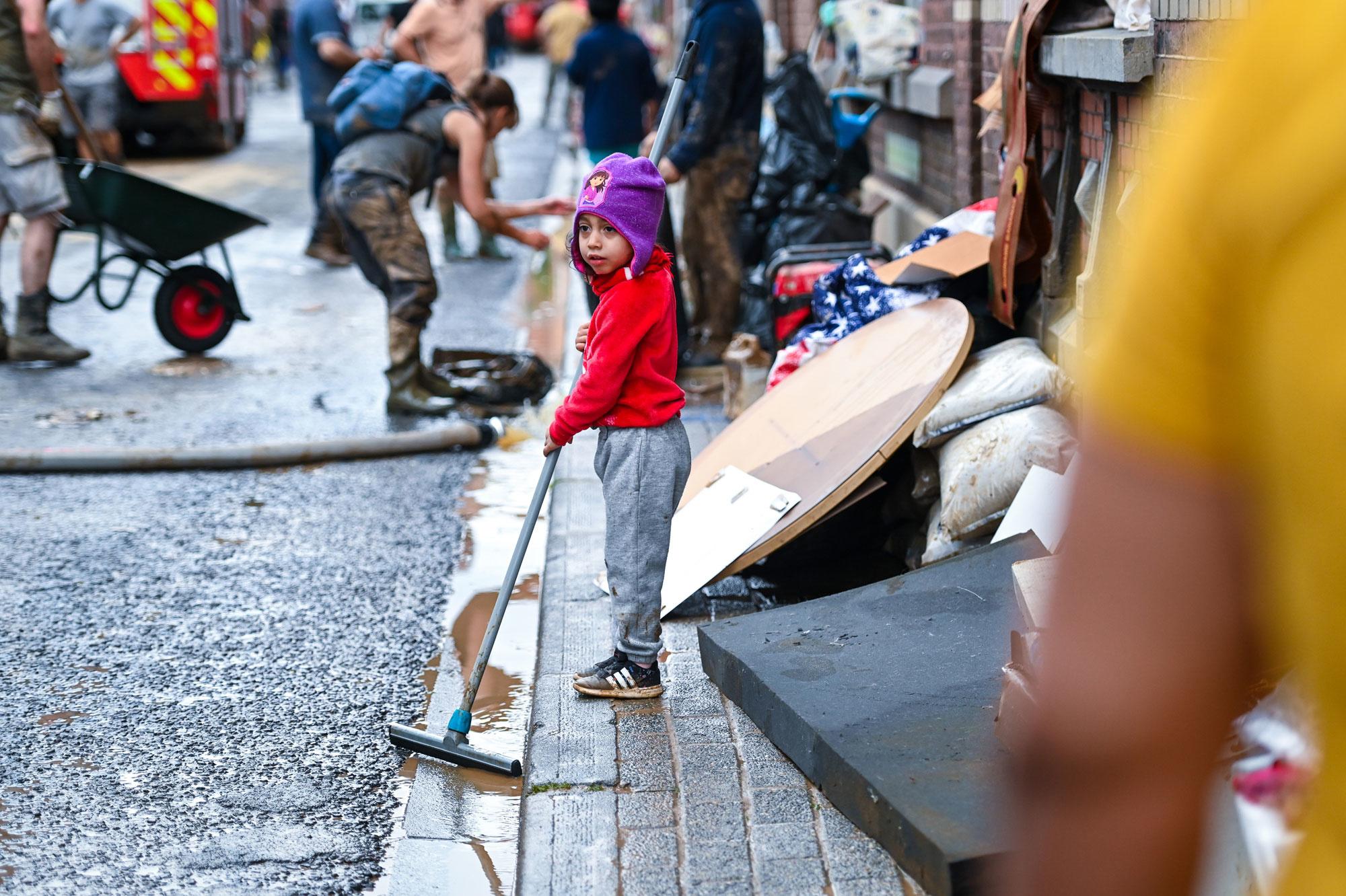 Een kind helpt bij het opruimen na de overstromingen in de stad Namen, 25 juli 2021.