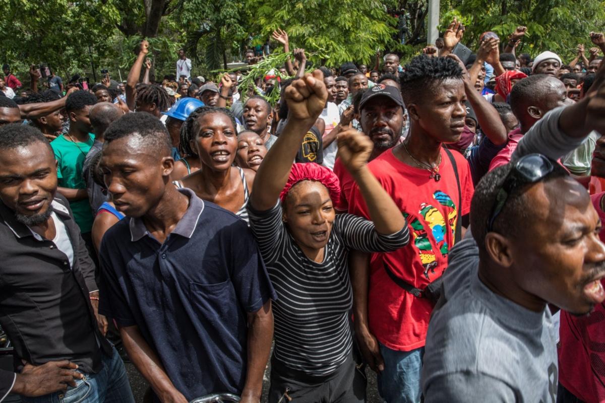 Haïtianen verzamelen aan het politiecommissariaat waar de verdachten van de moord op de presidenr worden vastgehouden. 