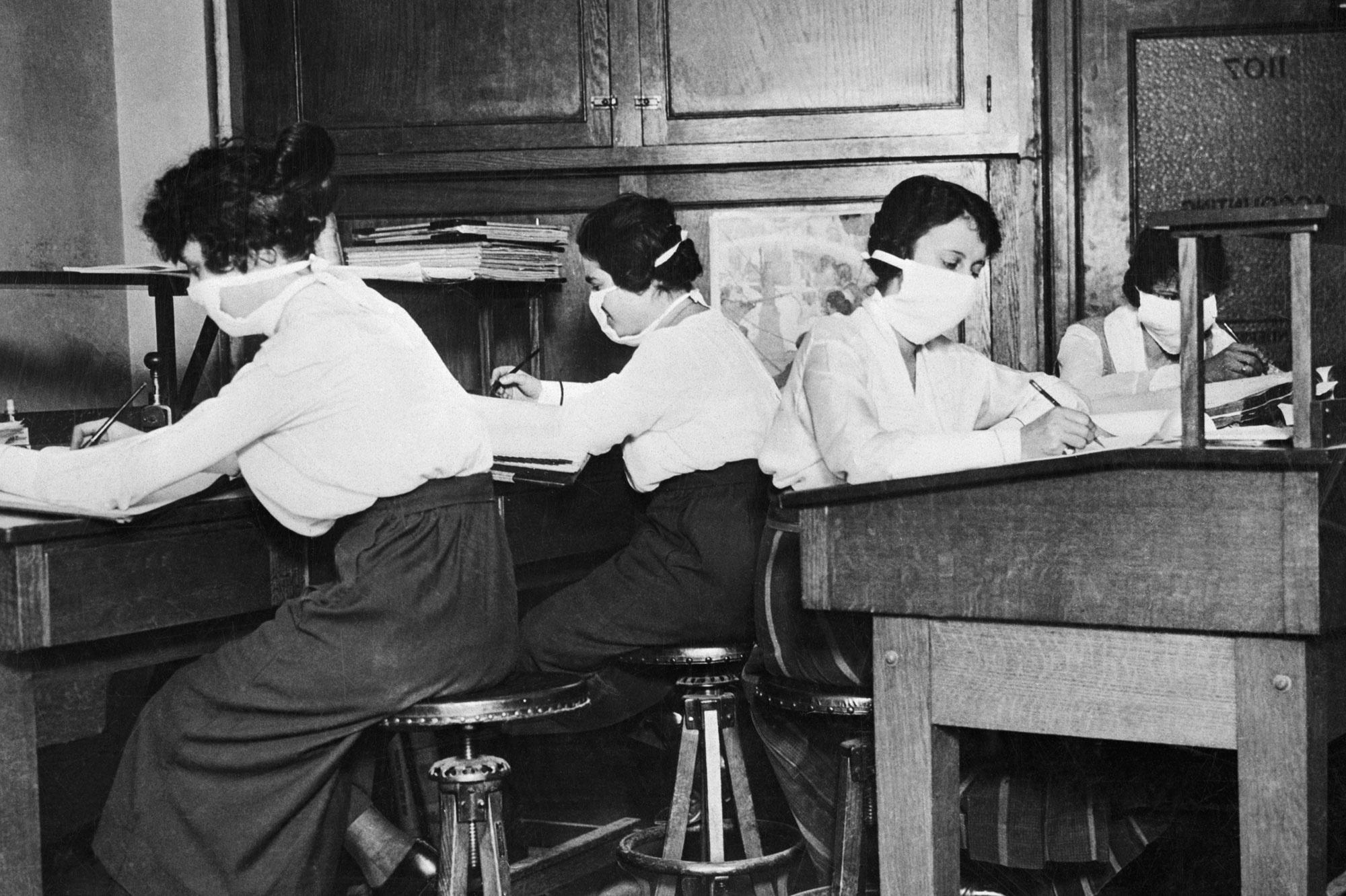 Vrouwen met mondmaskertjes op het werk.